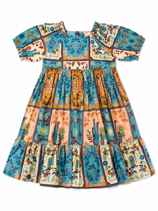 A short-sleeved tiered dress with a colorful patchwork print of blue, orange, beige, and pink floral panels, shown flat against a white background.