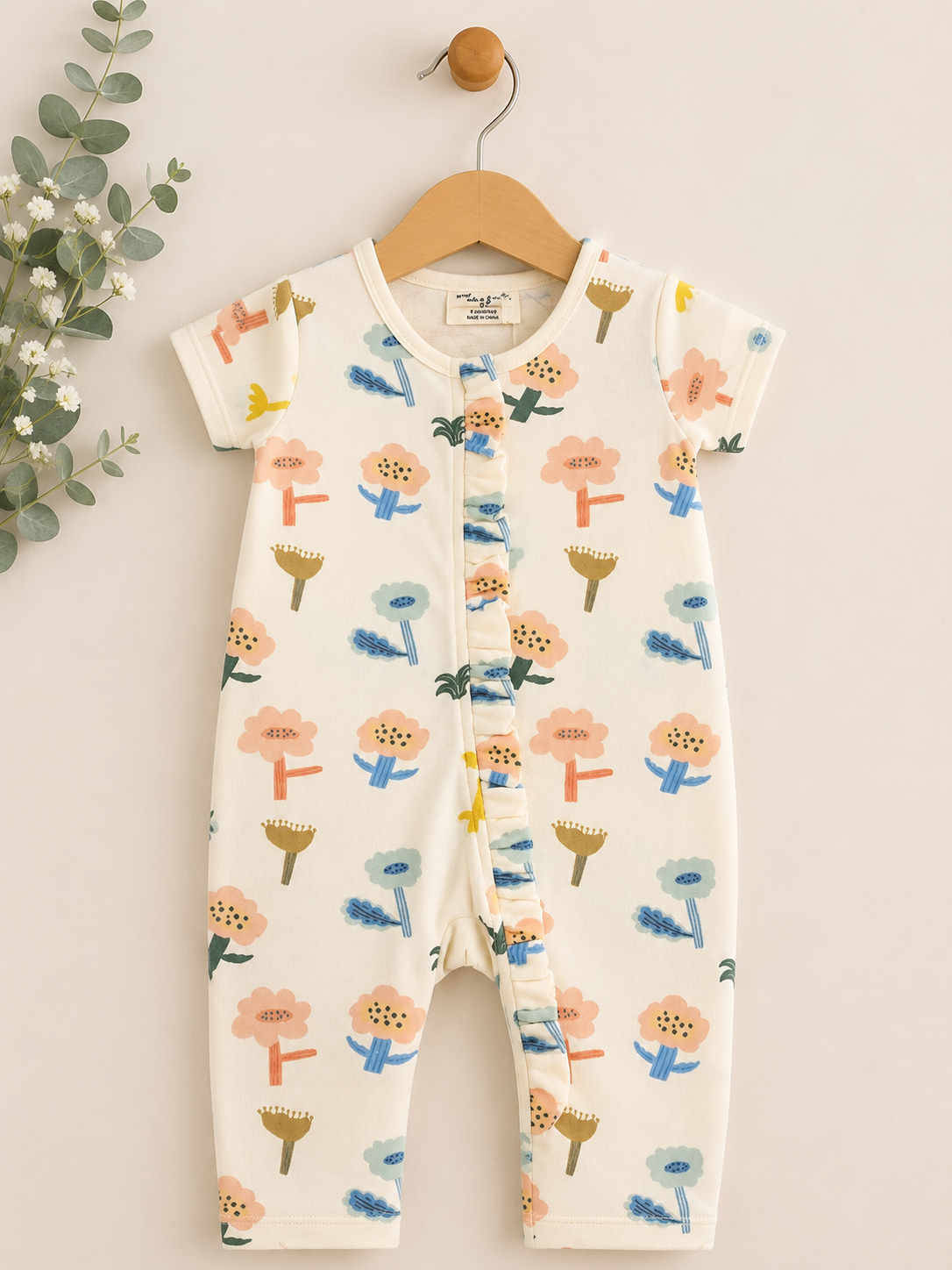 Baby romper with floral pattern on a hanger against a neutral background