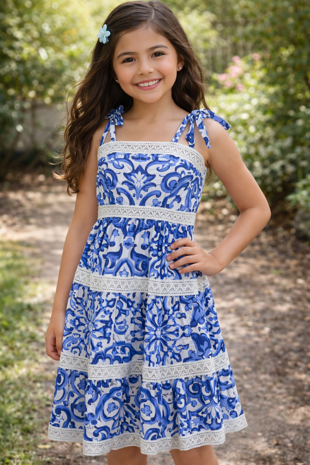 Young girl wearing a blue and white patterned dress outdoors.