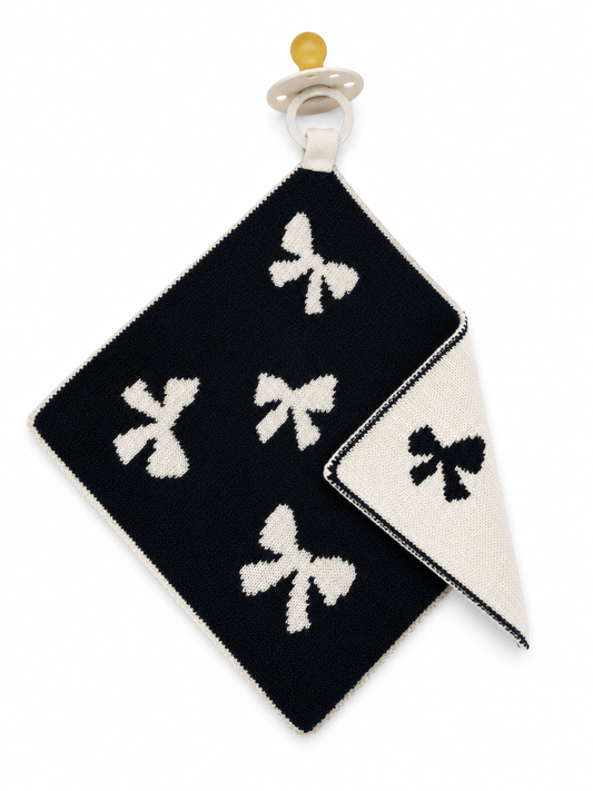 Black and white patterned baby blanket with bow design on a white background pacifier holder