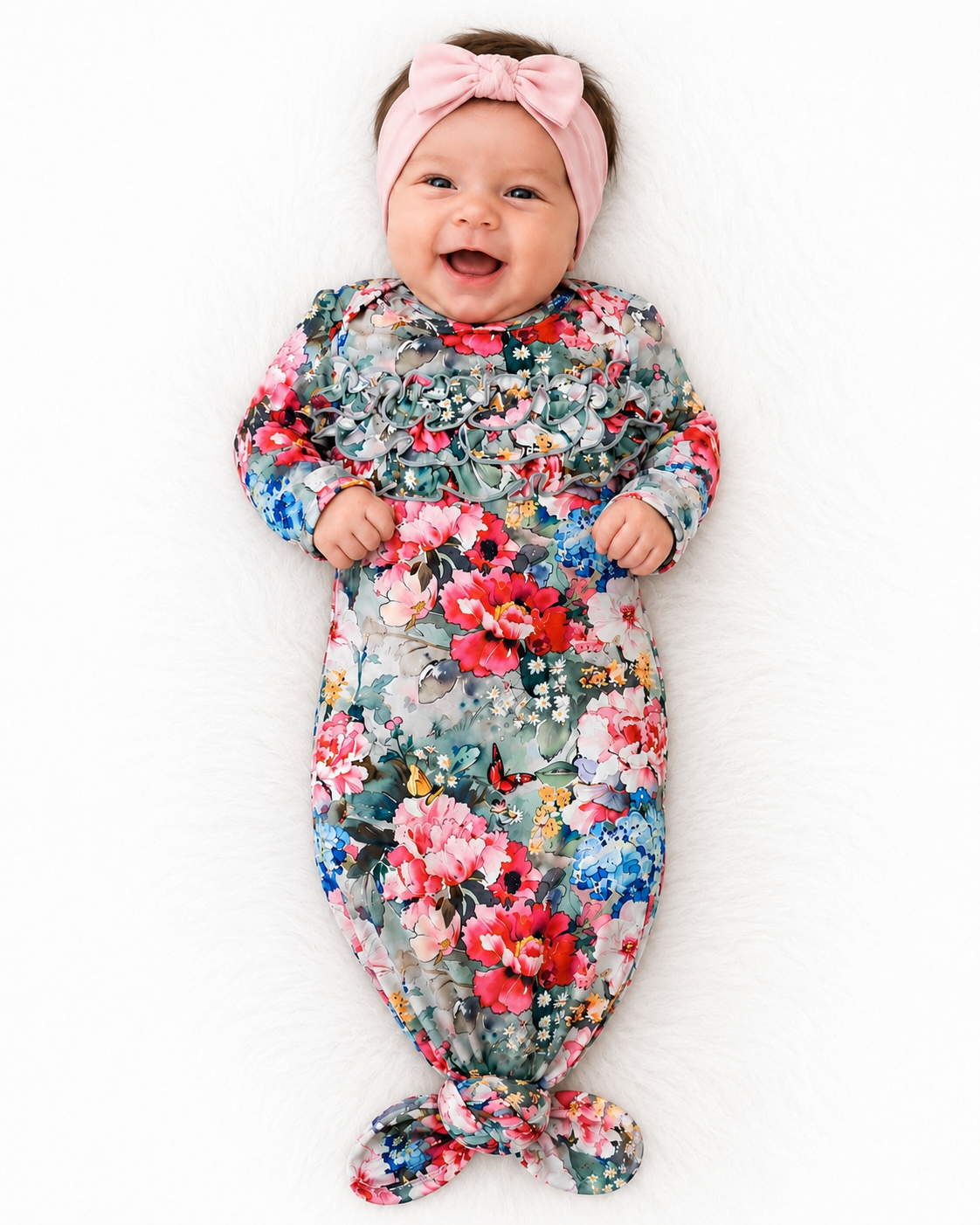 Baby girl in a colorful floral knot gown with a pink headband on a white background 