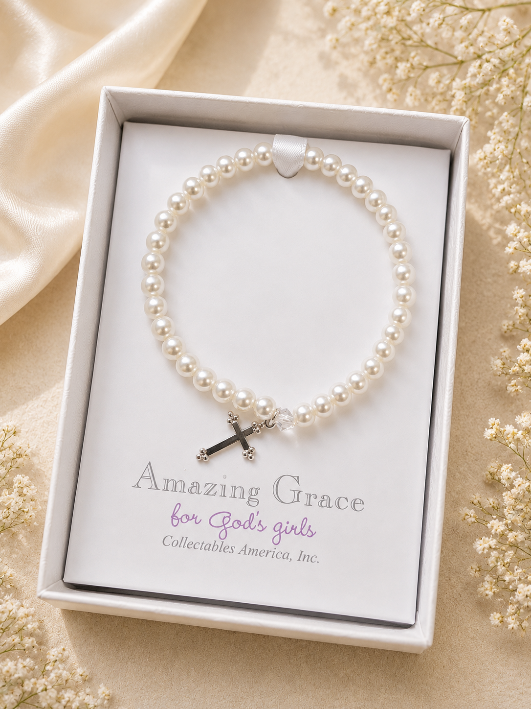 Pearl bracelet with a cross charm in a 'Amazing Grace' box on a beige background