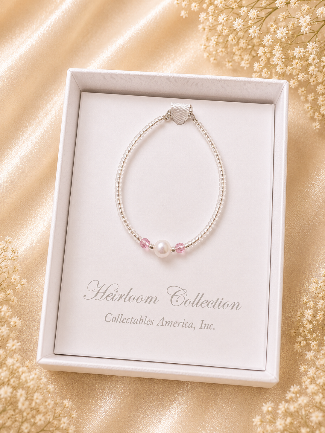 Pearl bracelet in a 'Heirloom Collection' box on a gold fabric background with flowers.