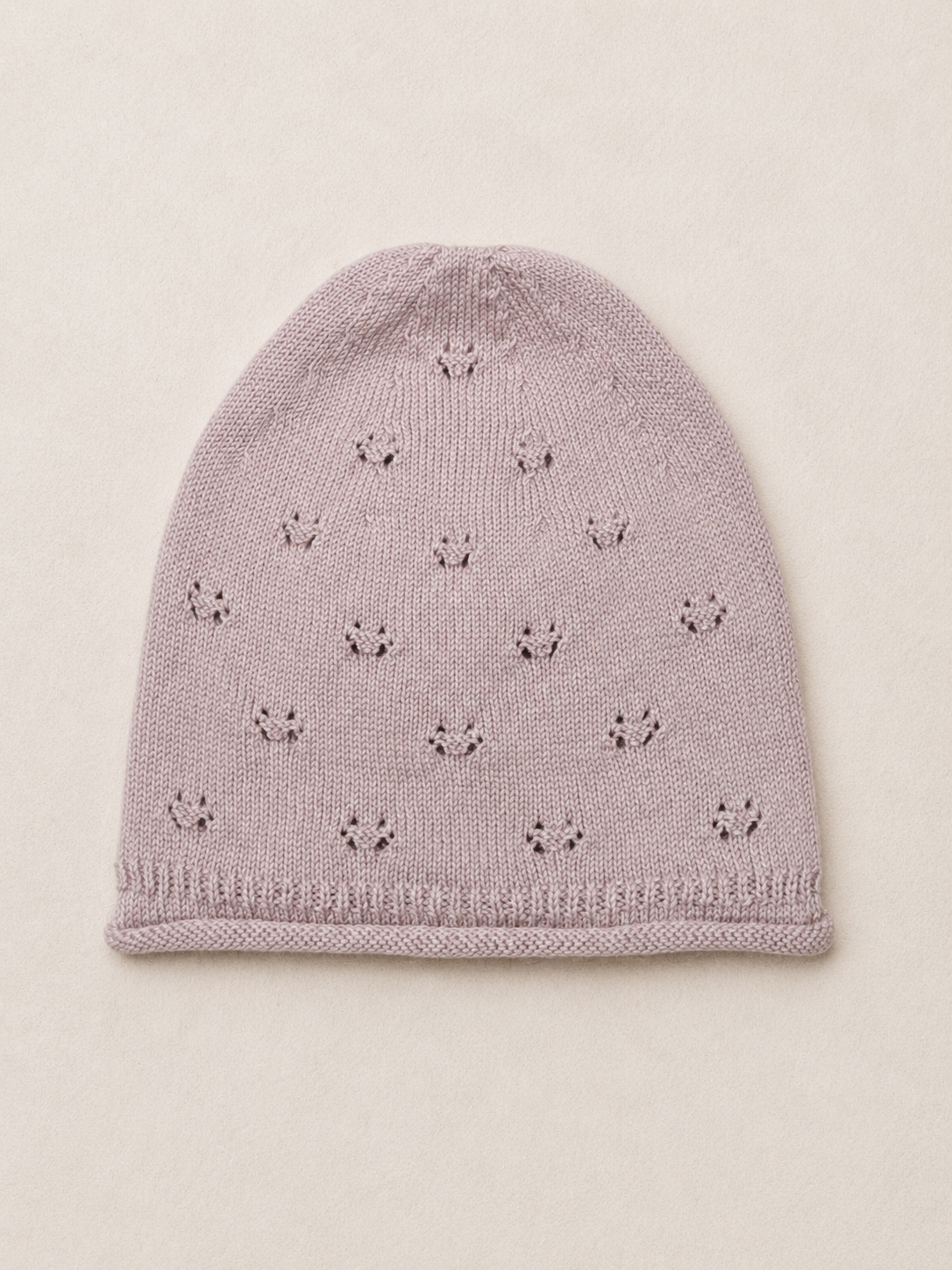 Knitted baby hat with star pattern on a beige background