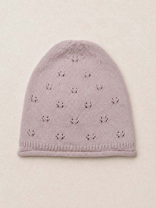 Knitted baby hat with star pattern on a beige background