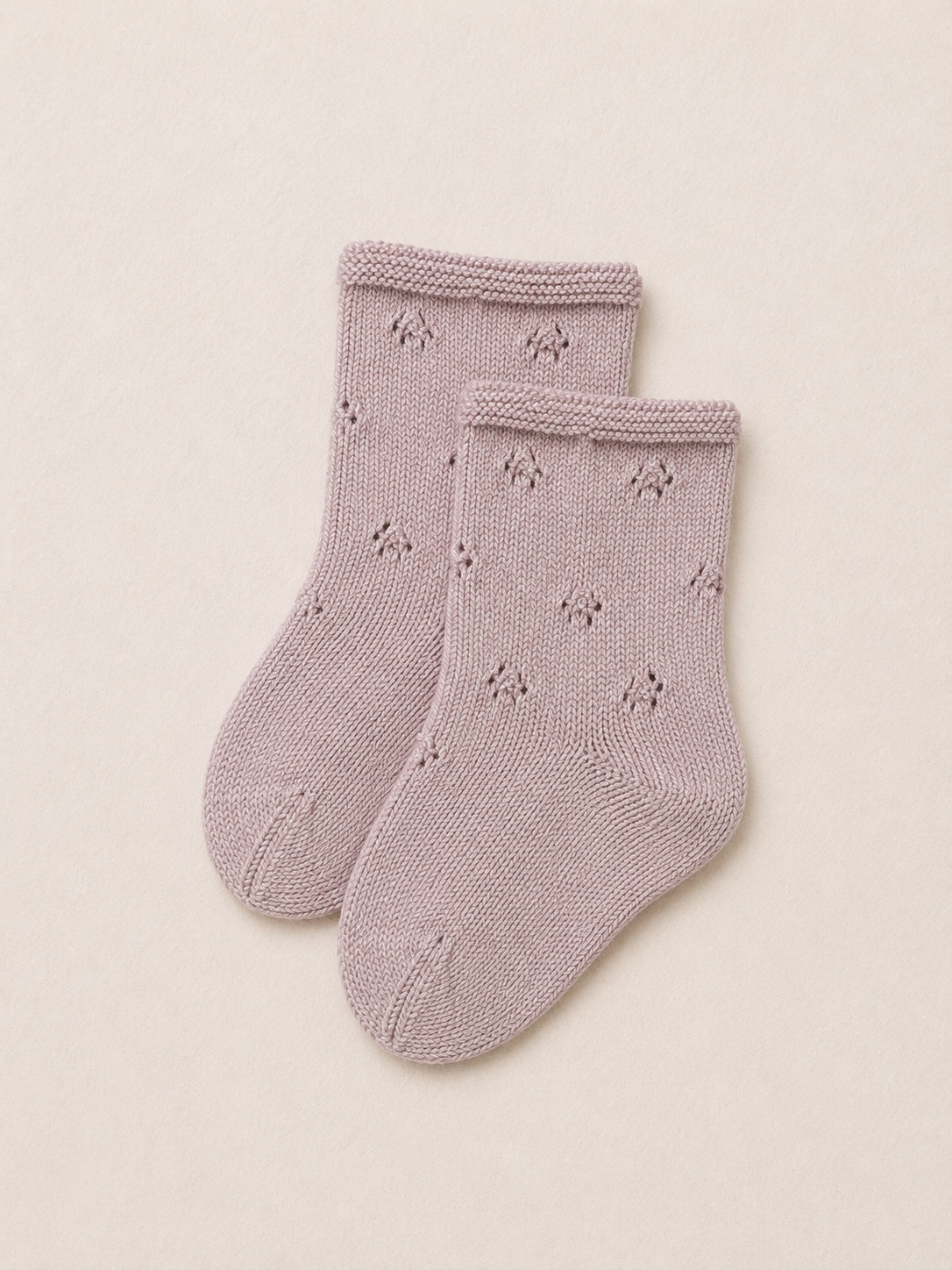 Pair of pink knitted socks with a subtle pattern on a beige background