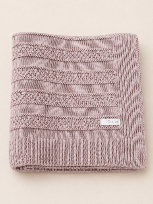 Knitted pink blanket with a brand label on a light beige background