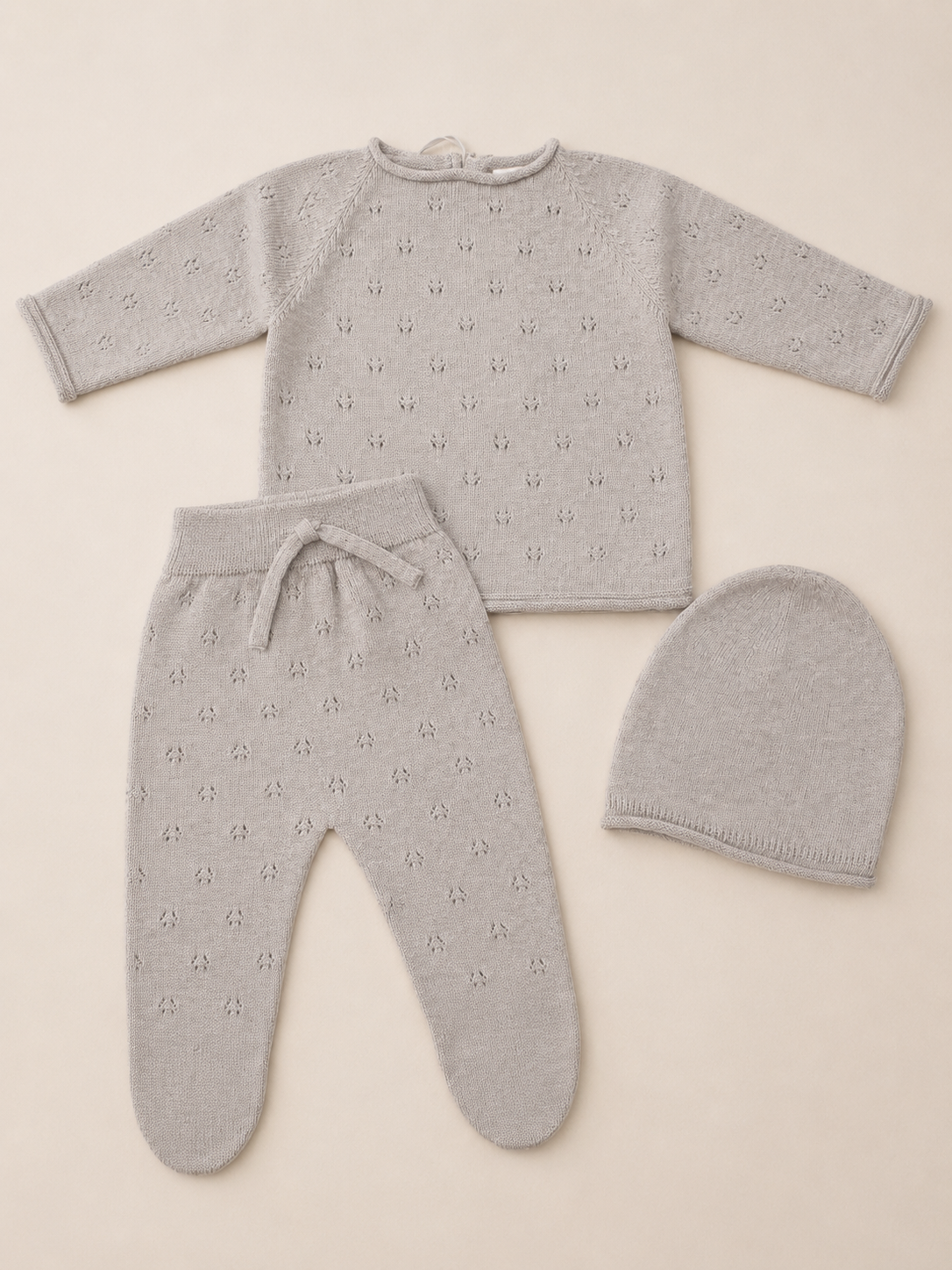 Tan baby outfit set with top, pants, and hat on a beige background