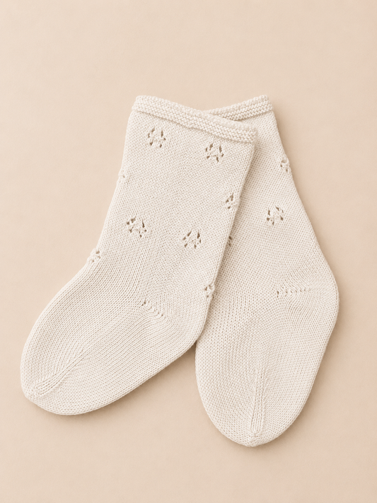 Pair of cream-colored socks with subtle patterns on a beige background
