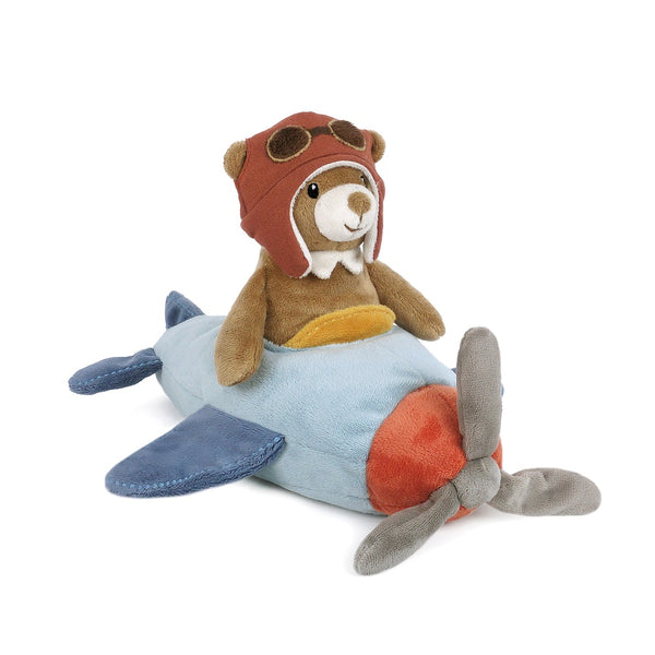 Plush toy bear in an aviator hat sitting on a toy airplane